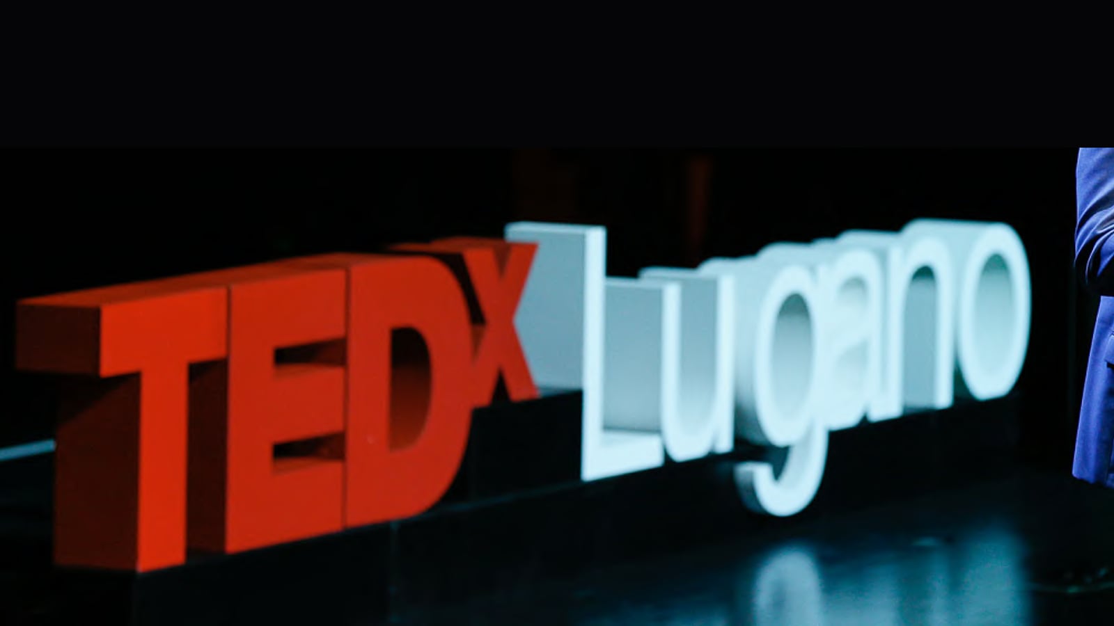 The TEDxLugano letters glowing on stage